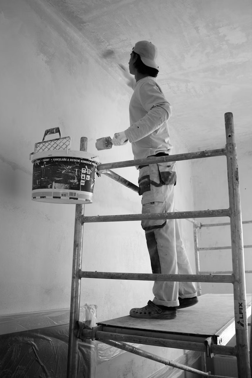 A decorator on a scaffold, painting a ceiling